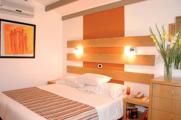 Schlafzimmer im Ghazala Beach Hotel mit Bett, Kopfteil, Nachttisch und Klimaanlage.