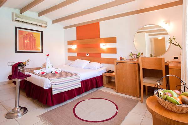 Innenansicht eines Hotelzimmers im Ghazala Beach Hotel mit Bett, Schreibtisch und Früchtekorb.