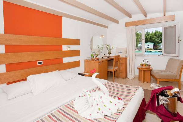 Innenansicht eines Zimmers im Ghazala Beach Hotel mit Bett, Schreibtisch, Fenster und Swimmingpool im Hintergrund.