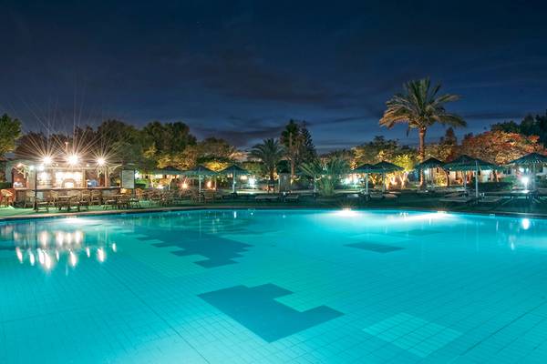 Der Pool des Ghazala Beach Hotels bei Nacht mit Beleuchtung und Liegestühlen.