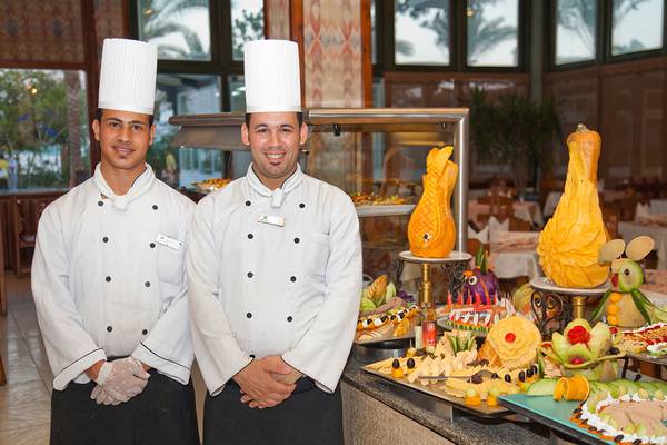 Zwei Köche im Ghazala Beach Hotel stehen vor einem Buffet mit verschiedenen Speisen.