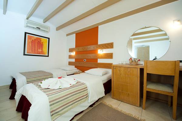 Zwei Betten im Hotelzimmer des Ghazala Beach mit gemusterten Laken, Kissen und einem Gemälde an der Wand.