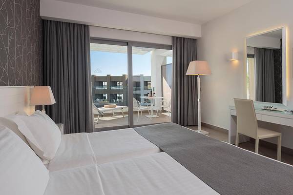 Doppelzimmer im Princess Andriana Resort & Spa mit großem Bett, Schreibtisch und Aussicht auf den Pool.