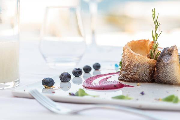 Fischgericht auf einem Teller mit Blaubeeren und Rosmarin, serviert im Princess Andriana Resort & Spa.
