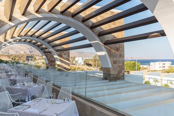 Außenterrasse des Princess Andriana Resort & Spa mit Blick auf das Meer und die Berge.