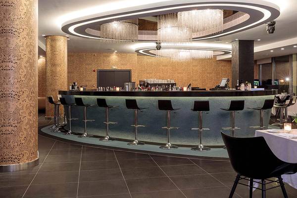 Innenansicht der Bar im Princess Andriana Resort & Spa mit modernen Möbeln und kristallenen Kronleuchtern.