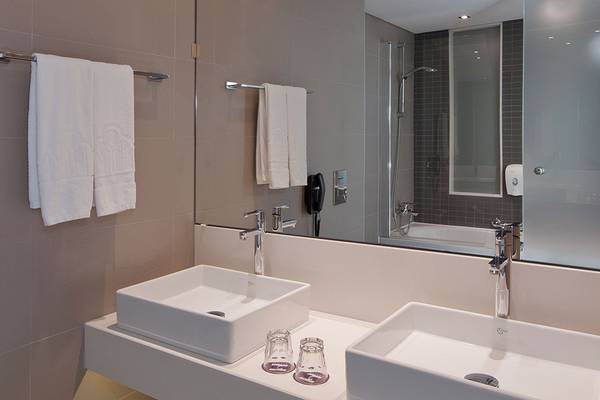 Ein Badezimmer mit zwei Waschbecken, Spiegeln und Handtüchern im Princess Andriana Resort & Spa.