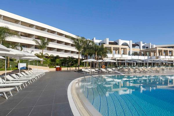 Außenpool des Princess Andriana Resort & Spa mit Sonnenliegen und Palmen.