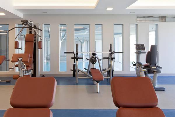 Fitnesscenter im Princess Andriana Resort & Spa mit verschiedenen Geräten und großen Fenstern.