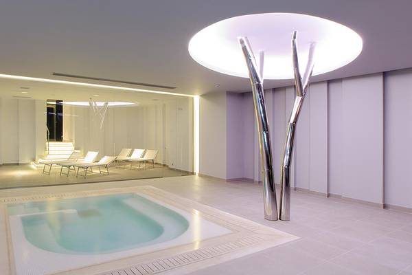 Innenbereich des Princess Andriana Resort & Spa mit einem Pool und Liegen.