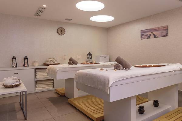 Massage-Raum im Princess Andriana Resort & Spa mit zwei Massagetischen, Kissen und Accessoires.