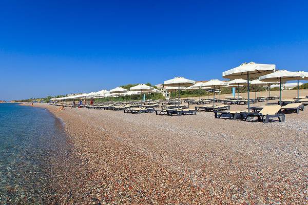 Strand des Princess Andriana Resort & Spa mit vielen Sonnenliegen und Schirmen.