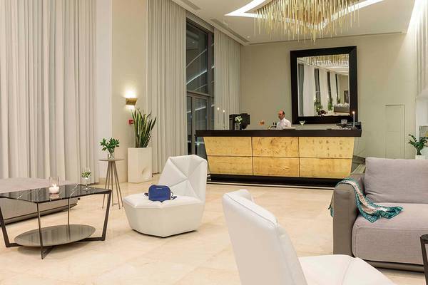 Empfangsbereich des Princess Andriana Resort & Spa mit Rezeption, Couch, Tischen und Pflanzen.