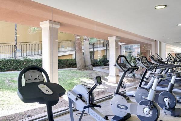 Fitnessstudio im Occidental Playa de Palma Hotel mit vielen Laufbändern und einer grünen Rasenfläche draußen.
