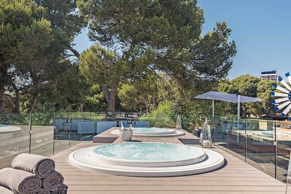 Hotelterrasse mit Whirlpools, einem Schirm und Blick auf Bäume und eine Windmühle