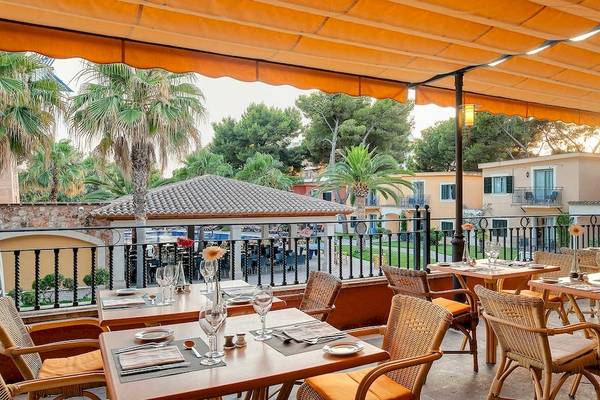 Außenterrasse des Occidental Playa de Palma Hotels mit gedeckten Tischen und Sonnenschirm.