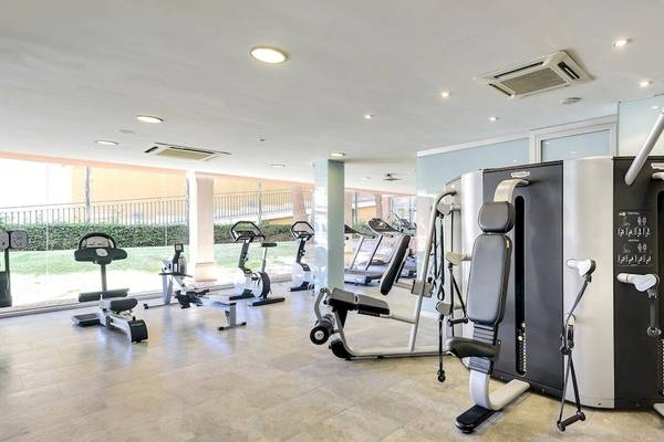 Fitnessstudio im Occidental Playa de Palma Hotel mit verschiedenen Trainingsgeräten und Blick auf den Garten.