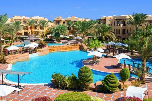 Außenbereich des Pools im Steigenberger Coraya Beach Resort mit Palmen und Liegestühlen.