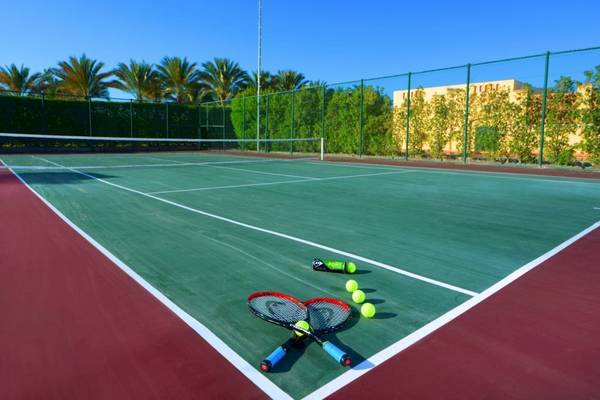 Tennisplatz im Steigenberger Coraya Beach Hotel mit zwei Tennisschlägern und Tennisbällen.