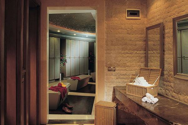 Innenansicht des Saunabereichs im Cornelia Diamond Golf Resort & Spa mit zwei Badewannen, roten Decken und weißen Handtüchern.