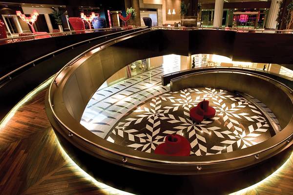 Innenbereich des Cornelia Diamond Golf Resort & Spa mit geschwungener Treppe und kreisförmiger Sitzanordnung.