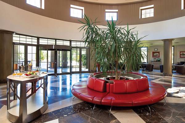 Die Lobby des Cornelia Diamond Golf Resort & Spa mit einer großen roten Sitzbank und einem großen Topfpflanzen.