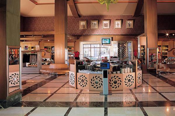 Empfangsbereich des Cornelia Diamond Golf Resort & Spa mit gemusterten Wänden und quadratischen Fliesenboden.