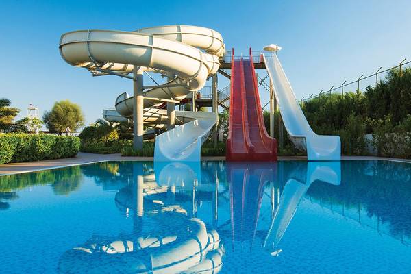 Ein Swimmingpool mit Wasserrutschen und einem roten Wasserfall im Cornelia Diamond Golf Resort & Spa