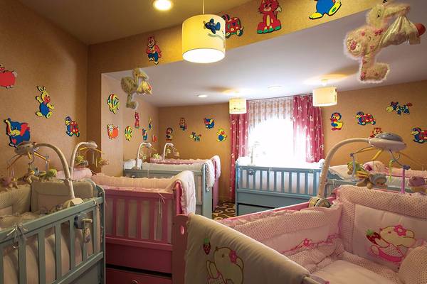 Kinderzimmer im Cornelia Diamond Golf Resort & Spa mit farbenfrohen Wandaufklebern und mehreren Babybetten.