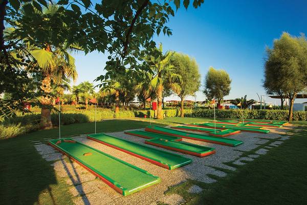 Minigolf-Kurs im Cornelia Diamond Golf Resort & Spa mit grünen und roten Grüns auf gepflegtem Rasen.