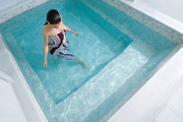 Eine Frau steht im blauen Wasser eines kleinen Beckens im Cornelia Diamond Golf Resort & Spa.