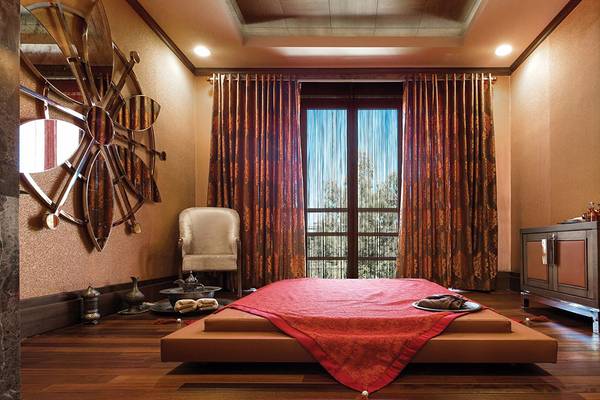 Schlafzimmer im Cornelia Diamond Golf Resort & Spa mit großem Bett, rotem Bettlaken, Fenstern und Vorhängen.