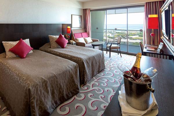 Doppelzimmer im Cornelia Diamond Golf Resort & Spa mit zwei Betten, Blick auf das Meer und ein Champagner im Eiskübel.