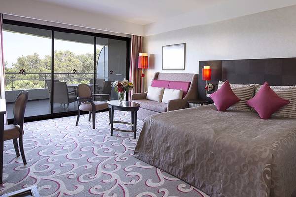 Hotelzimmer im Cornelia Diamond Golf Resort & Spa mit Bett, Couch, Tisch, Stühlen und Balkon.