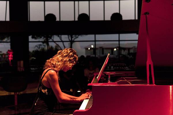 Eine Musikerin spielt ein rotes Klavier im Cornelia Diamond Golf Resort & Spa.