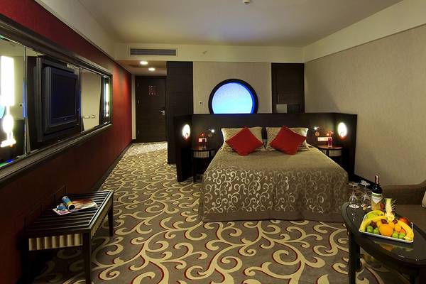 Ein Hotelzimmer im Cornelia Diamond Golf Resort & Spa mit einem großen Bett, Fernseher und einem Esstisch mit Früchten.