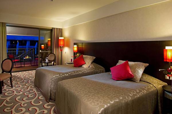 Doppelzimmer im Cornelia Diamond Golf Resort & Spa mit Balkon, Fernseher, Schreibtisch und zwei Betten.