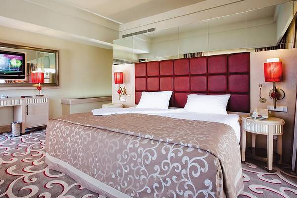 Schlafzimmer im Cornelia Diamond Golf Resort & Spa mit Doppelbett, Nachttischen und Fernseher.