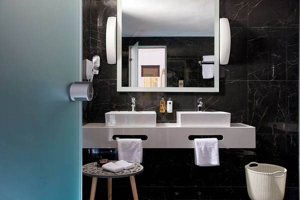 Badezimmer im Mythos Palace Resort & Spa mit zwei Waschbecken und Marmorwänden.
