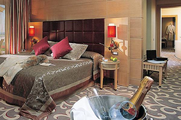 Hotelzimmer im Cornelia Diamond Golf Resort & Spa mit einem großen Bett, roten Kissen und einem Blick auf das Meer.