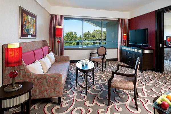 Innenansicht der Hotelsuite im Cornelia Diamond Golf Resort & Spa mit Sofa, Fernseher und Balkon