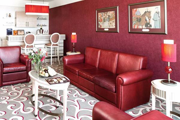 Wohnzimmer im Cornelia Diamond Golf Resort & Spa mit rotem Ledersofa, Esstisch und Dekor.
