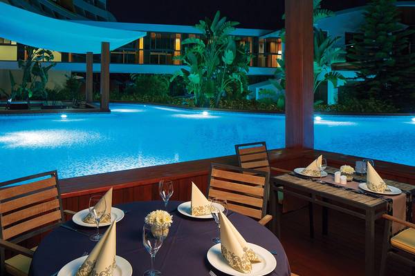 Außenbereich des Cornelia Diamond Golf Resort & Spa bei Nacht mit Swimmingpool und Tisch.