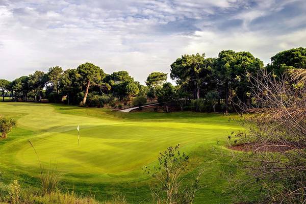 Golfplatz im Cornelia Diamond Golf Resort & Spa mit dichtem Baumbestand und klarem Himmel.