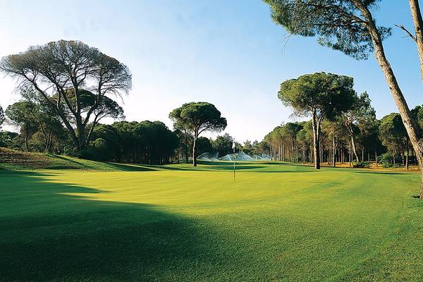 Golfplatz des Cornelia Diamond Golf Resort & Spa mit gut gepflegtem Rasen und umliegenden Bäumen.