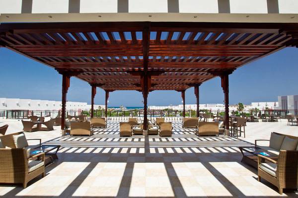 Hotelterrasse mit Sonnenschattierungen und Blick auf den Ozean.