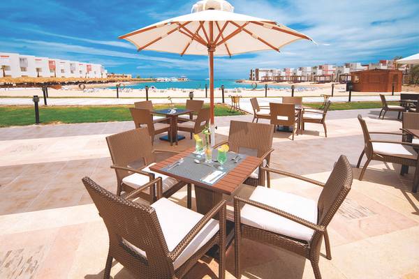 Außenbereich des Sunrise Crystal Bay Resorts mit einem Tisch, einem Schirm und Blick auf den Strand.