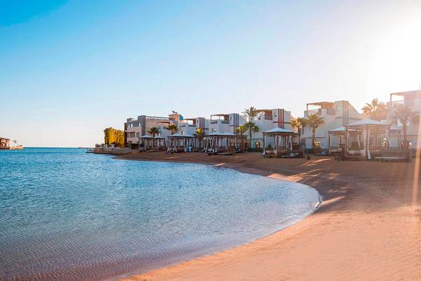 Strandansicht des Sunrise Crystal Bay Resorts mit Gebäuden und Palmen am Wasser