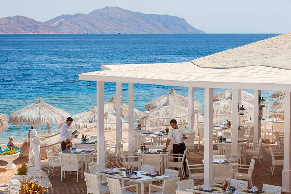 Außen-Essbereich des Sunrise Crystal Bay Resorts mit Blick auf das Meer und die Berge.