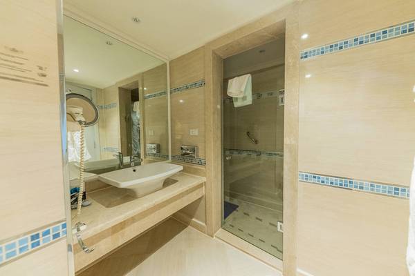 Badezimmer des Sunrise Crystal Bay Resorts mit Waschbecken, Spiegel und Glasdusche.